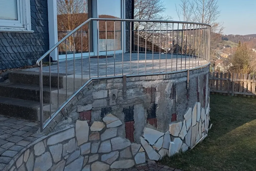 Edelstahlgeländer auf einer Natursteinmauer an einer Treppe